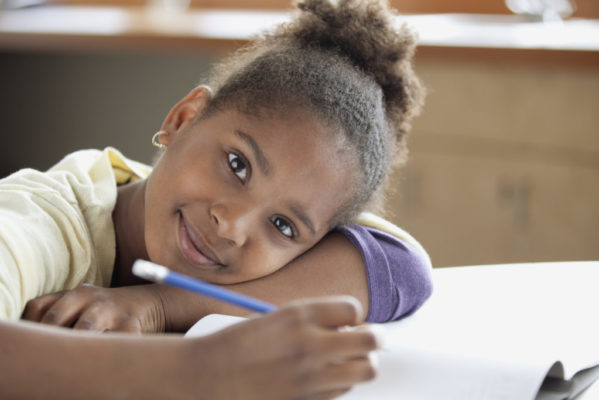 African American middle school student leaning on school desk. African American middle school student leaning on school desk.