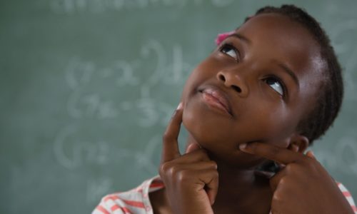 Schoolgirl sitting against chalkboard